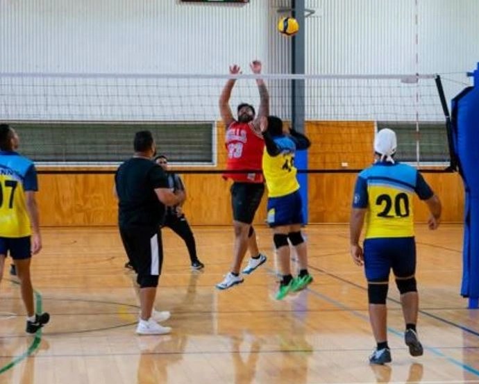 Players contest the ball at the net during an indoor volleyball match.